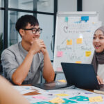 Multiracial group of young creative people in smart casual wear discussing business brainstorming meeting ideas mobile application software design project in modern office. Coworker teamwork concept.